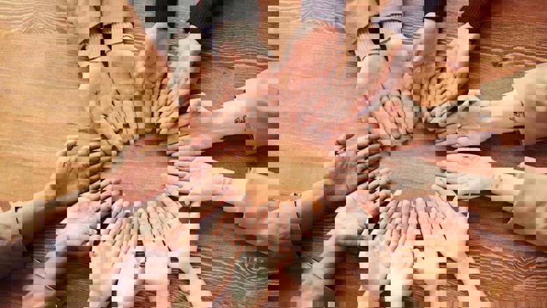 Photo Of People's Hand On Top Of Wooden Table 